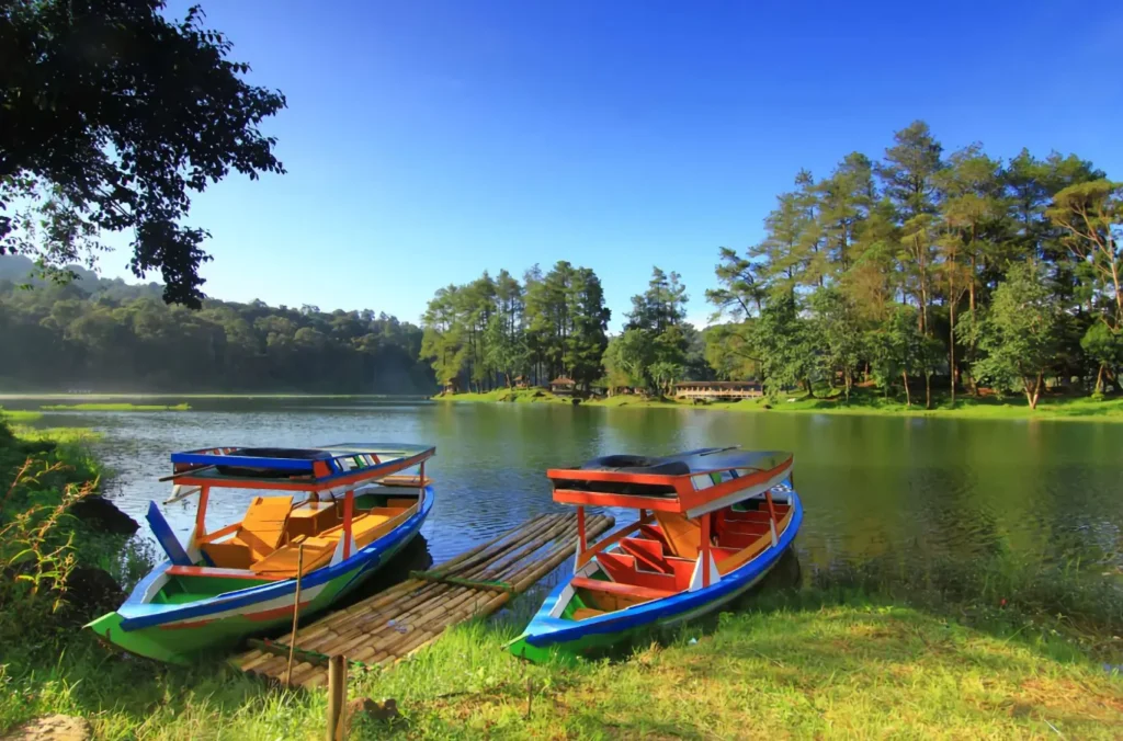 Perahu wisata di tepi danau Situ Patenggang, dikelilingi pepohonan hijau dan suasana sejuk